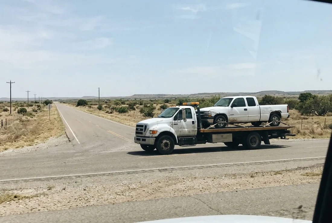Flatbed carrying a pickup truck on a road in Williamson County